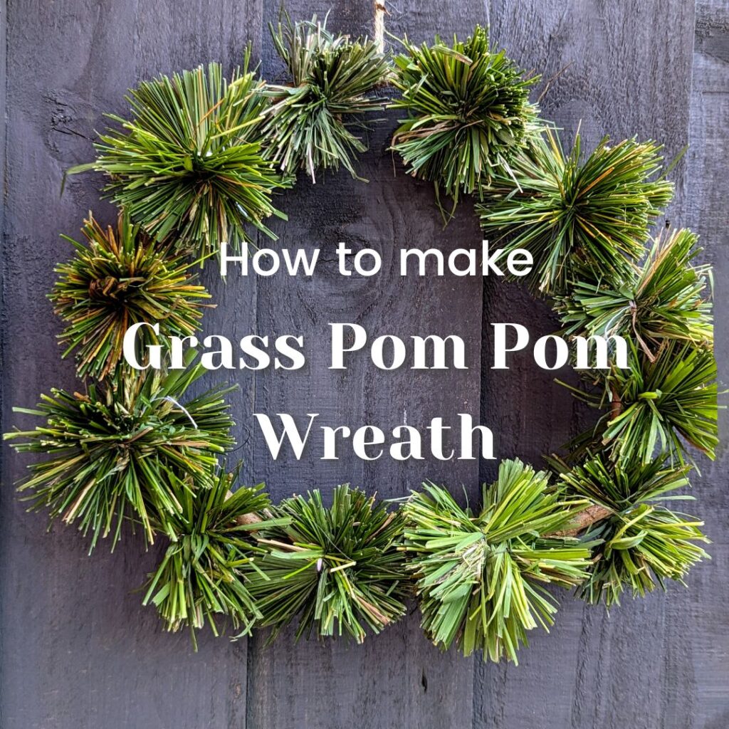 A wreath made out of grass pom poms hung on a door for outdoor decoration for a nature craft.